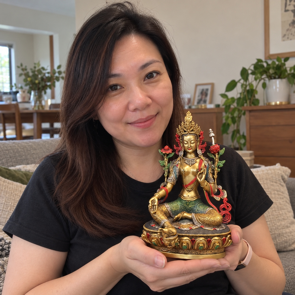 Green Tara statue held in a home setting
